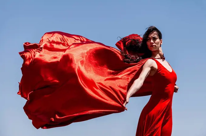Beautiful female dancer with red scarf looking away against clear sky on sunny day