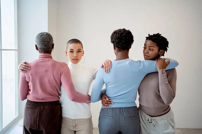 Female friends embracing each other in living room