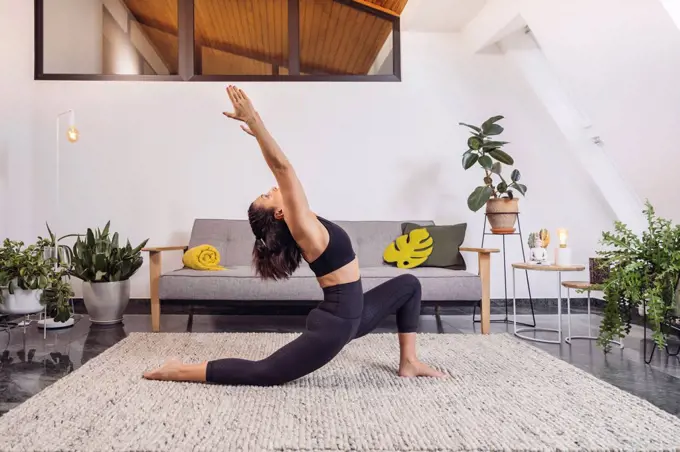 Woman practicing Yoga pose against sofa in living room at home