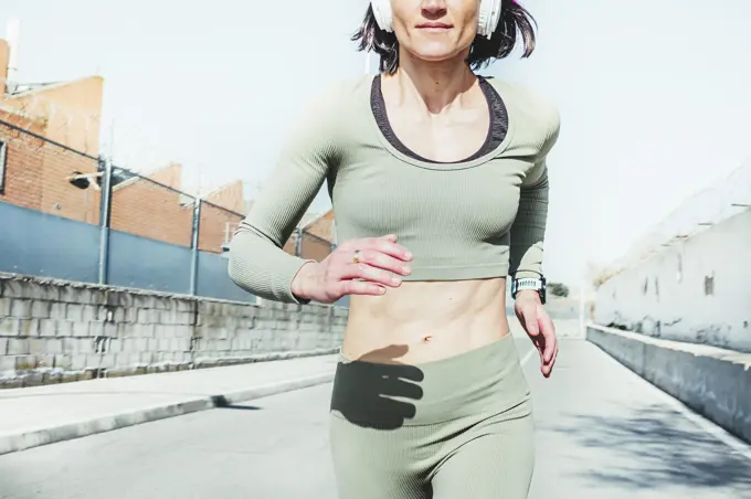 Woman in sports clothing running against sky