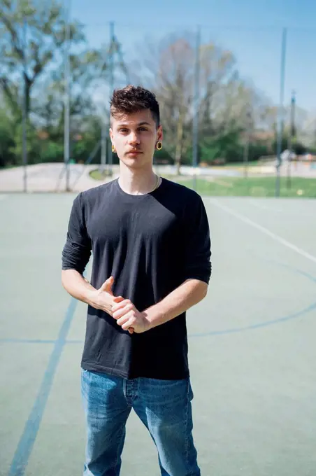 Young hipster man standing at sports court during sunny day