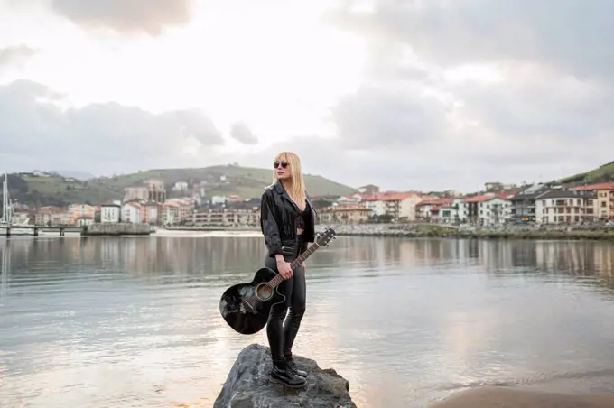 Beautiful woman looking away while standing on rock at lake