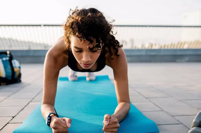 Female athlete exercising in plank position on exercise mat