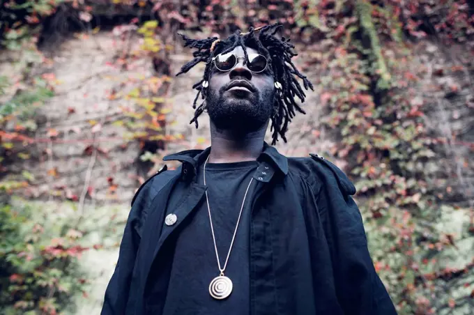 Man with locs hairstyle standing in front of wall