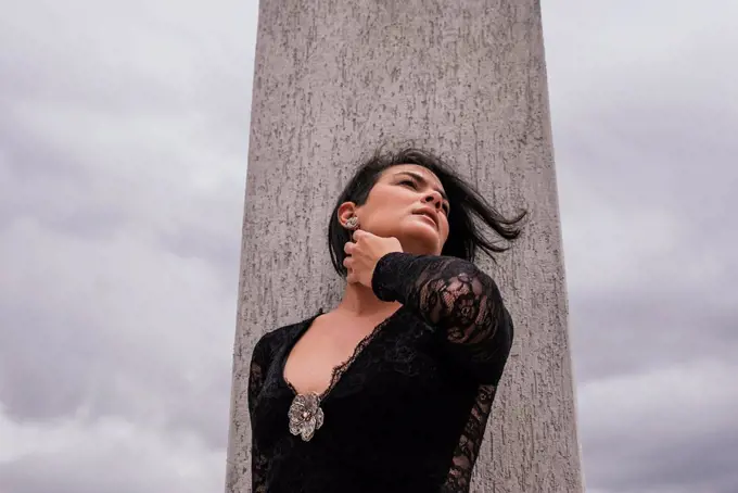 Thoughtful woman looking away while standing in front of architectural column