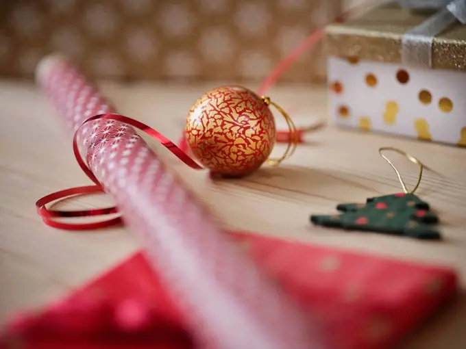 Gift wrapping paper with ribbon and Christmas decoration on table