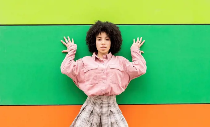 Curly hair woman leaning on colorful wall