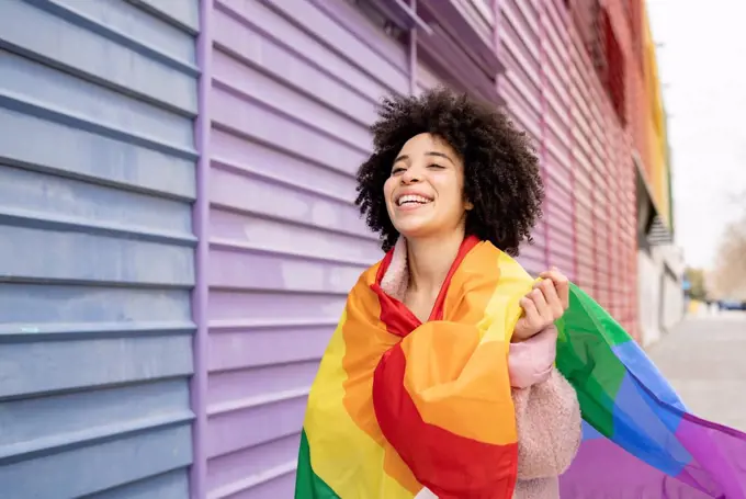 Cheerful woman wrapped in rainbow flag