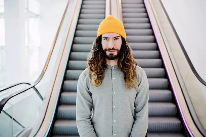 Handsome man in knit hat standing in front of escalator