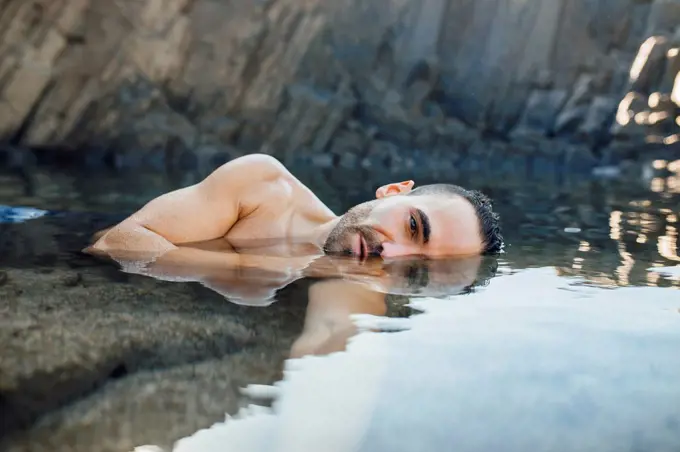 Shirtless man floating on water during vacations