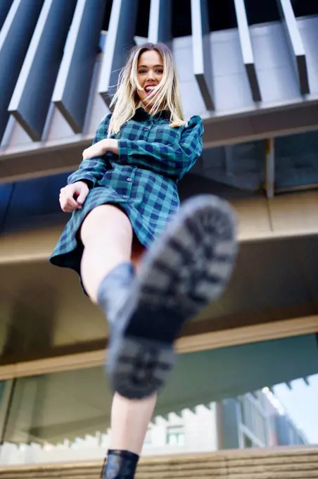 Cheerful woman kicking in front of building