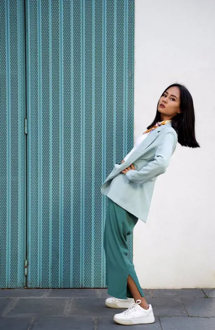 Fashionable young woman with hand on hip bending backward by wall