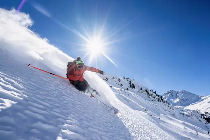 Sun shining over man skiing in¶ÿArlberg¶ÿmassif