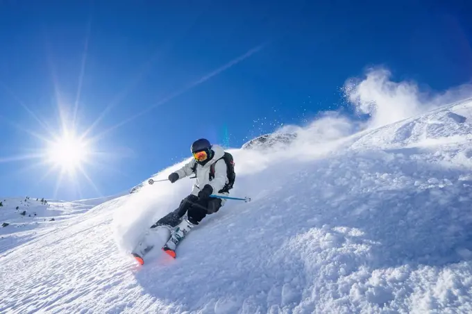 Sun shining over young man skiing in¶ÿArlberg¶ÿmassif