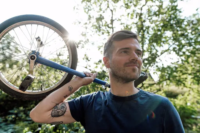 Man with unicycle looking away during sunny day