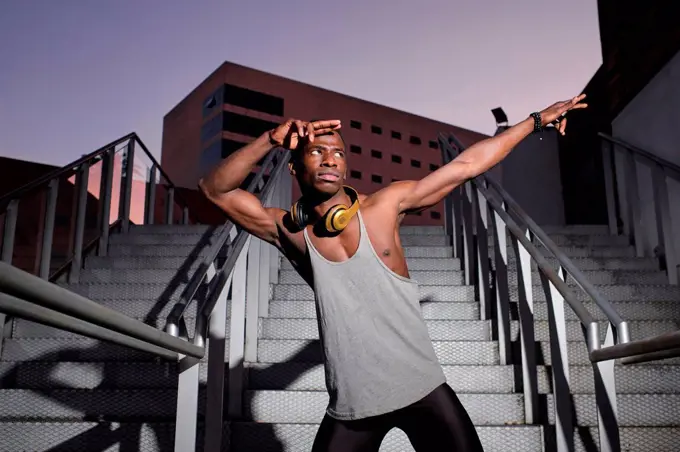 Young man in dab pose while standing on metal staircase