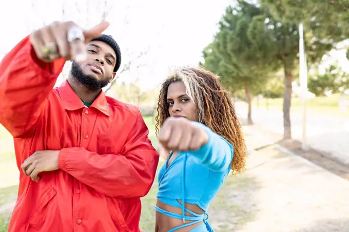 Female and male friends gesturing while standing in park