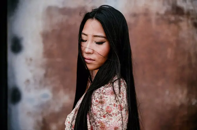 Beautiful woman with eyes closed by rusty iron door