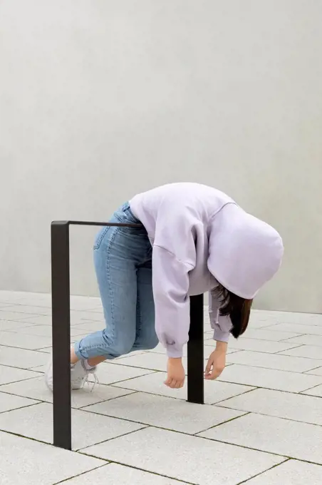 Girl hanging on metal by wall