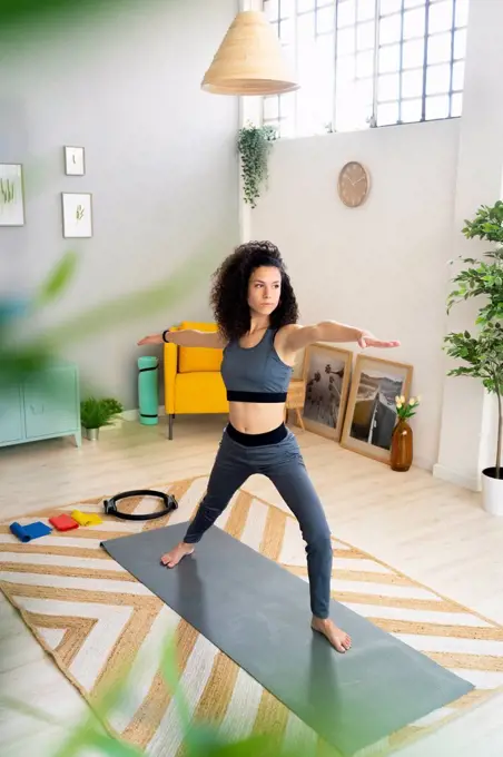Young woman practicing warrior pose at home