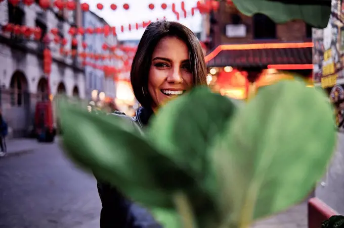 Happy young woman in front of plant in city