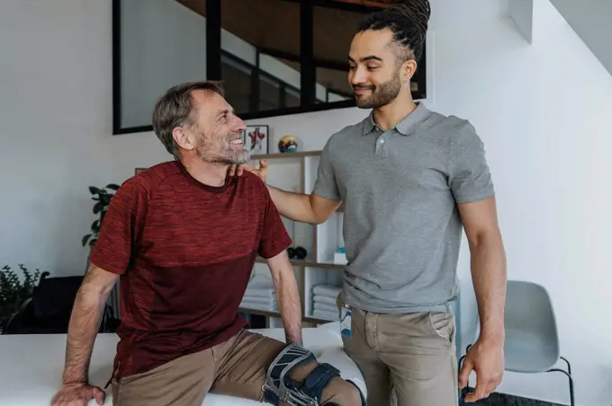 Male physiotherapist with smiling patient in medical practice