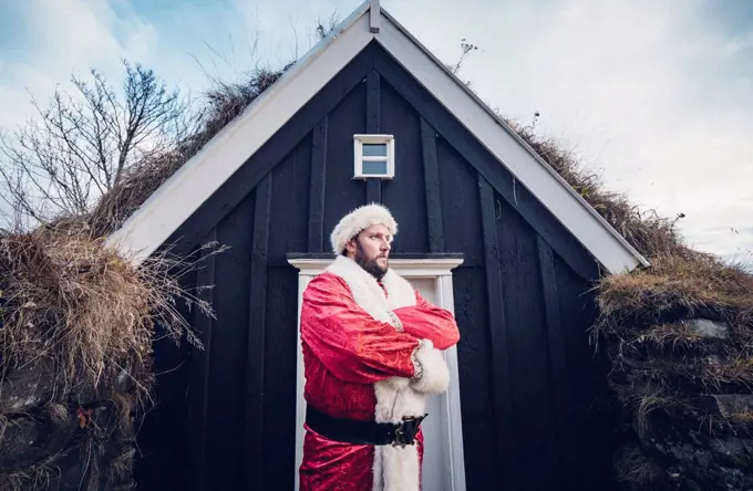 Iceland, Santa Claus standing in front of cabin looking at distance