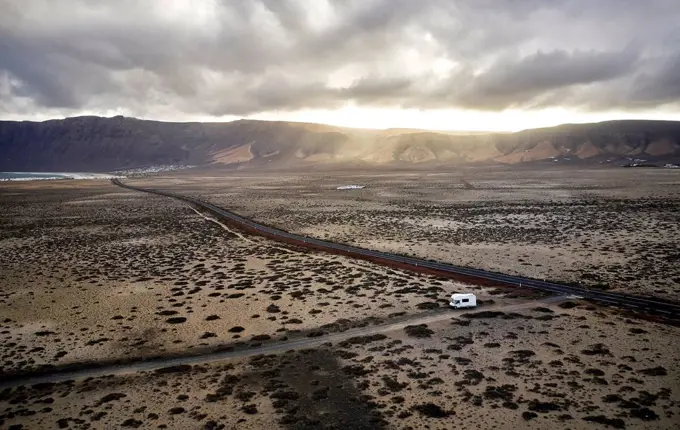 Spain, Canary Islands, Aerial view of motor home driving along gravel road at Lanzarote island