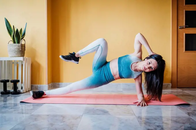 Sportswoman practicing strength training exercise on mat at home