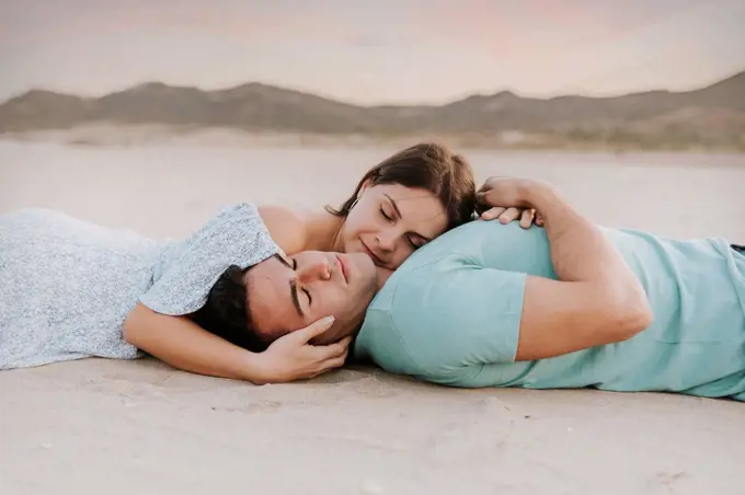 Young woman leaning on man at beach during sunset