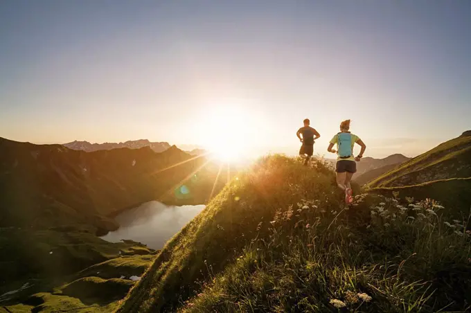 Germany, Allgaeu Alps, man and woman running on mountain trail