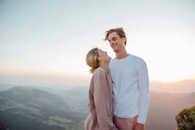 Switzerland, Grosser Mythen, happy young couple standing in mountainscape at sunrise