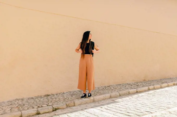 Female tourist looking away while standing on footpath