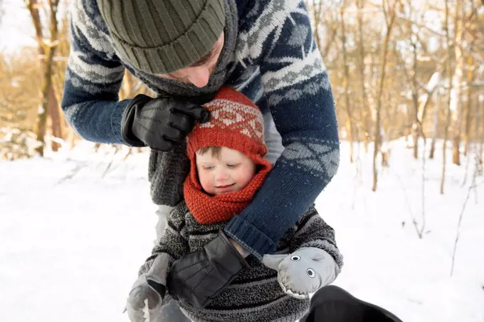 Father adjusting knit hat of son during winter