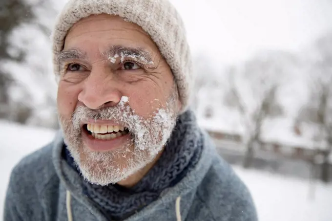 Smiling man looking away with snow on face during winter