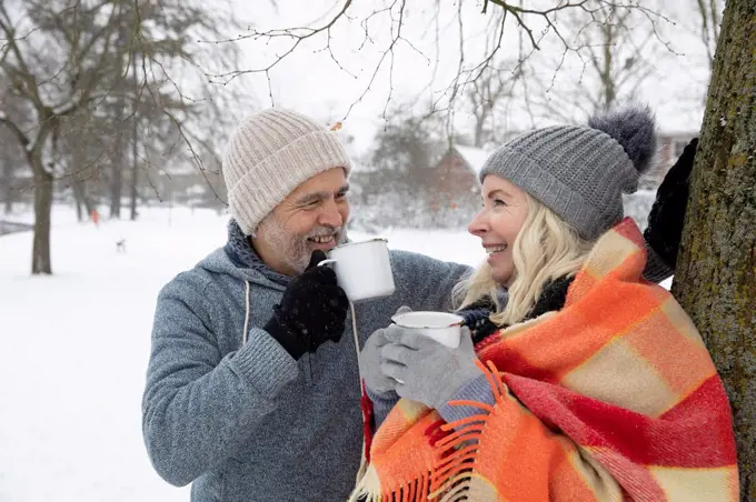 Smiling senior couple drinking tea in mug during winter