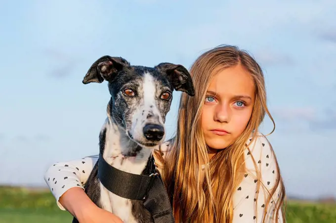 Blond girl with greyhound looking away