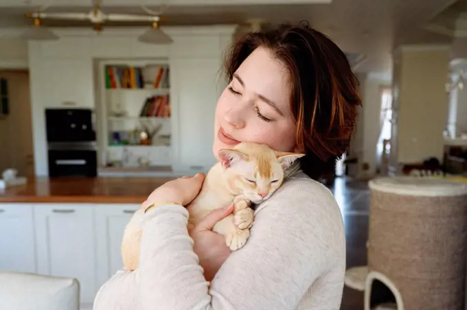 Beautiful woman embracing cat at home