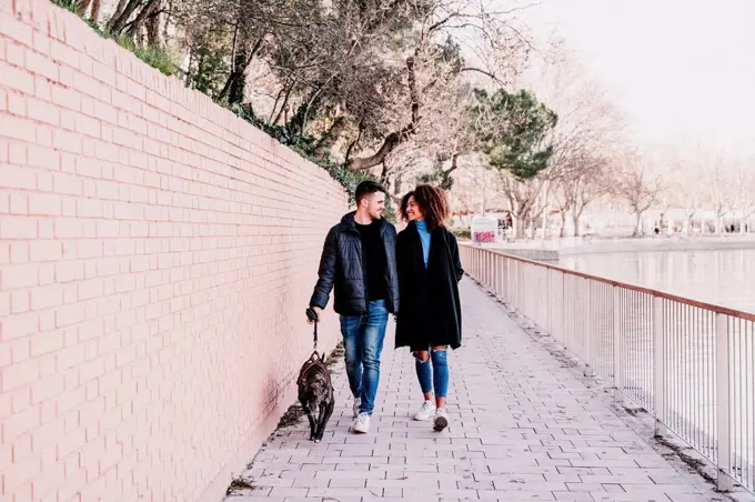 Young couple walking with dog on footpath