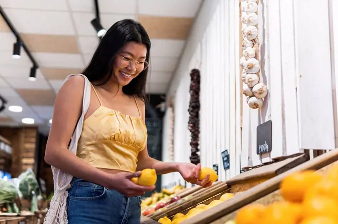 Smiling woman buying lemons at grocery store