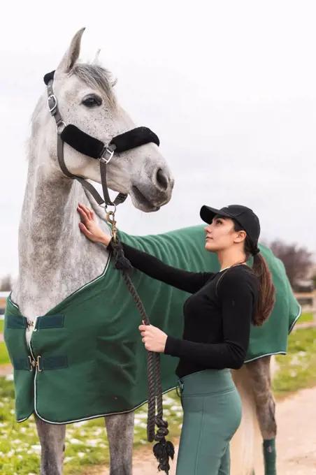 Young woman stroking horse outdoors