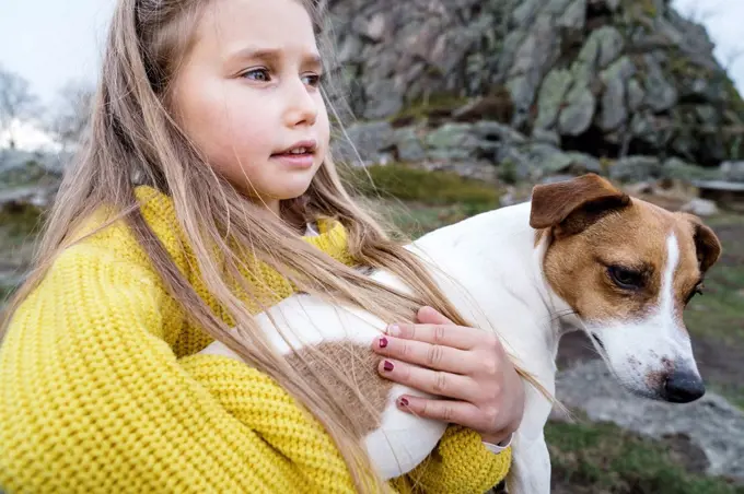 Blond girl carrying Jack Russell Terrier looking away