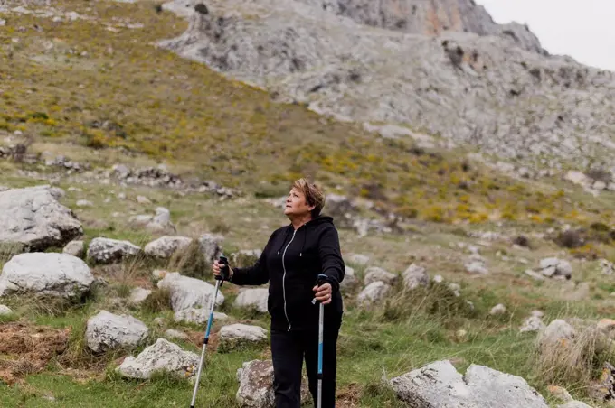 Senior woman in sports clothing hiking on mountain