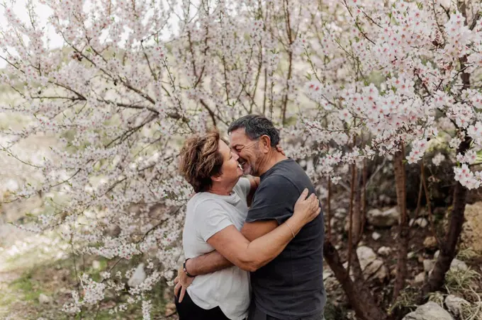 Senior couple embracing each other by tree