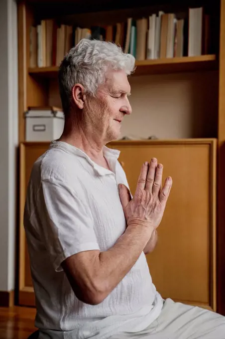 Man with hands clasped meditating at home