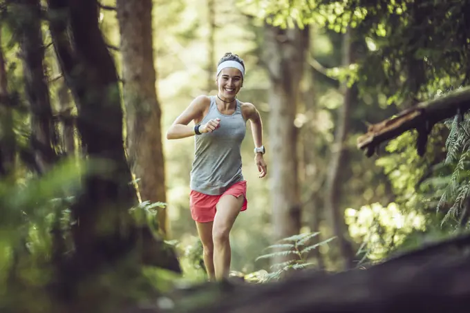 Excited female athlete running in forest