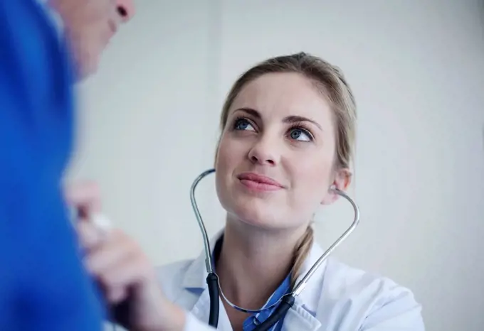 Female doctor checking senior patient with stethoscope in hospital