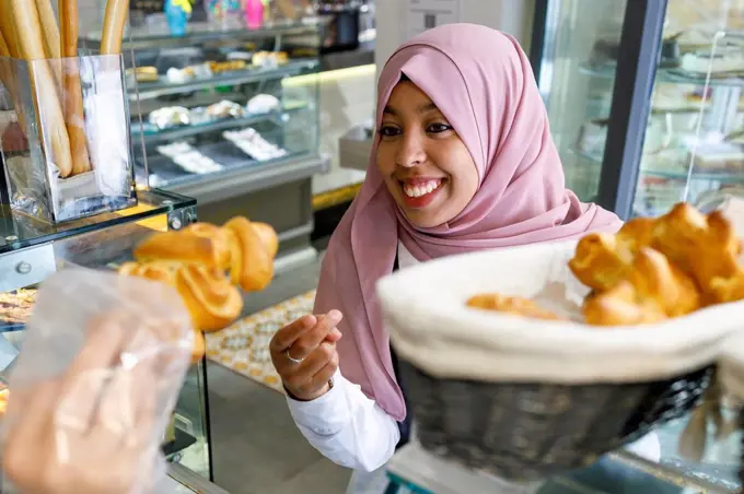 Happy woman buying pastry in bakery