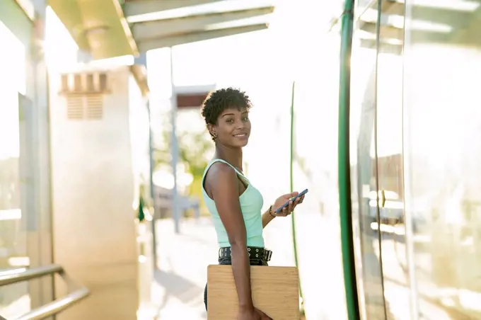 Young young woman standing at tram entrance with wireless technologies