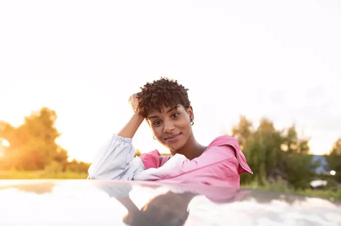 Young woman with head in hand on car outdoors